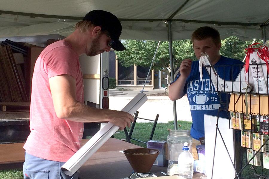 Andrew Dilbeck, a senior communications studies major, buys a poster from Jason Baran on Monday during the Back-To-School Poster Sale in the Library Quad. This discount sale is sponsored Pyramid America who sells posters to people all over the country.