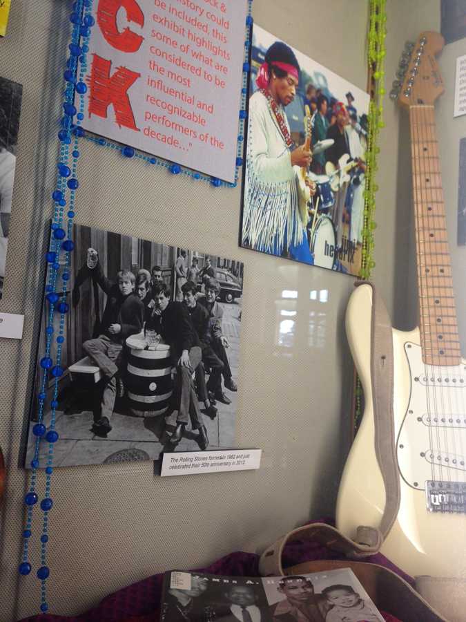 A guitar emulating Jimi Hendrixs left-handed guitar leans on a wall detailing rock in the 60s and the impact it made on music. This display is one of the many in Booth Library setting the scene for this semesters library exhibit focusing on everything to do with the 60s.