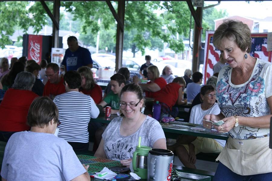 Fourth of July Committee member Betty Coffrin collects money from players during the Harold Hackett Memorial Bingo Game June 28 in Morton Park. Players were charged 25 cents per bingo board and could purchase as many as they like.