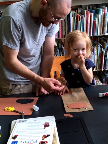 David Cook II and his daughter, Opal, 2 make a monkey puppet during Curiosity Day, on Saturday in Booth Library. Curiosity Day recognized the 70th anniversary of Curious George.