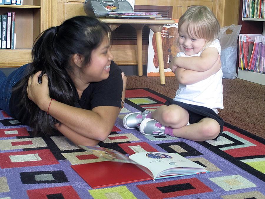 FILE PHOTO
Gladys Valentin, a senior elementary education major and the President of LASO, reads a book with Aubrey Malak, a three year old Charleston resident, during Latino Hertiage Story Time on Sept. 26 in Booth Library.