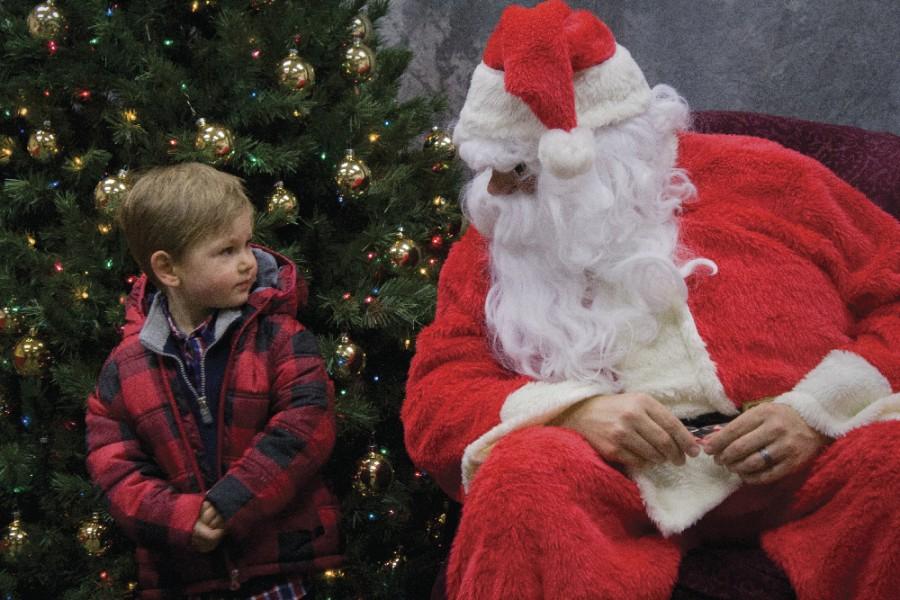 2-year-old Dean Hazelrigg, whose father Todd Hazelrigg is a junior physics major, stands next to Santa for a picture last Saturday at the Festival of Trees.