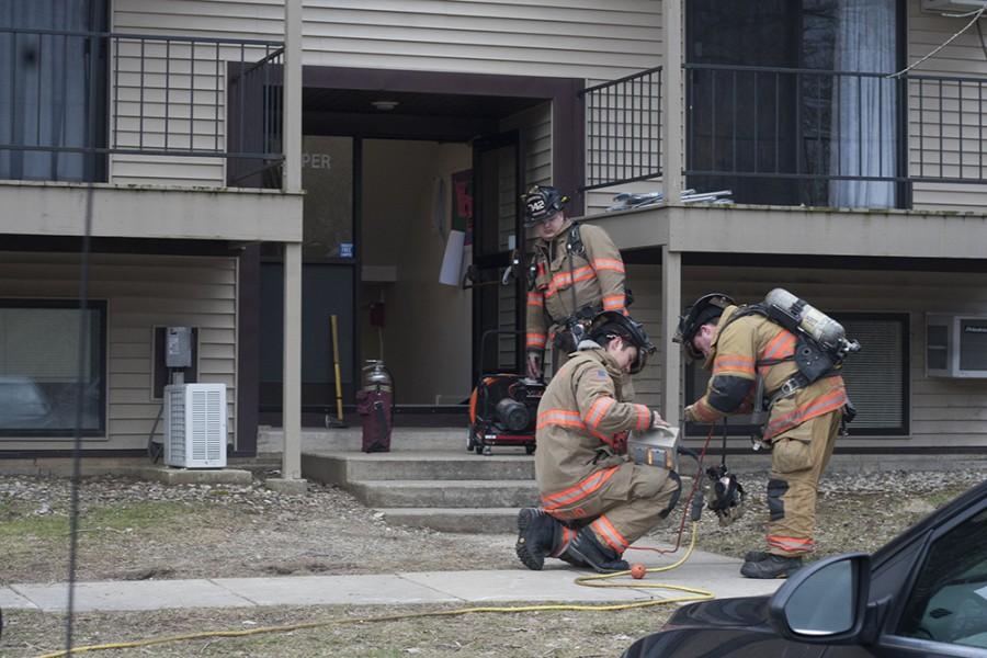 Three firefighters hook up a fan to the power source coming from the fire engine to ventilate one of the apartments in the Cooper Building at University Court Sunday.