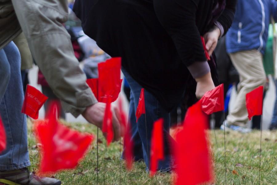 Red Flag March participants plant flags on the grounds of the Coles County Courthouse on Wednesday. 261 flags were planted at the Courthouse, representing every laid off Eastern employee to date.