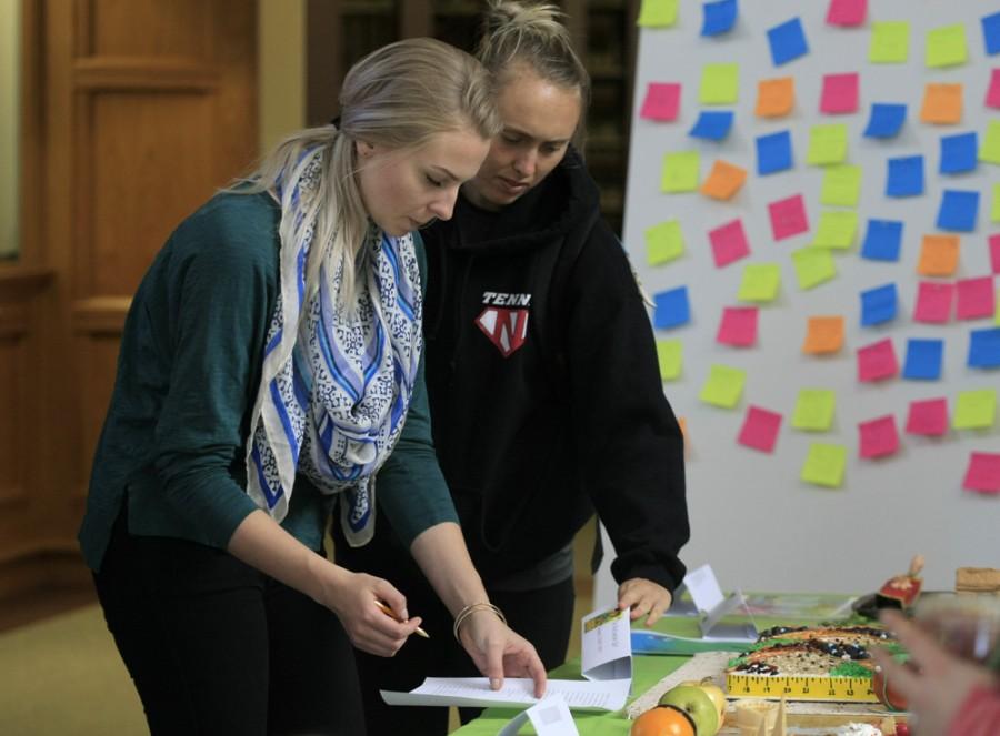 Erin Sutherland along side Alex Curtis, both senior family and consumer sciences majors, vote for their favorite edible book on Monday in Booth Library for the Edible Book Festival.