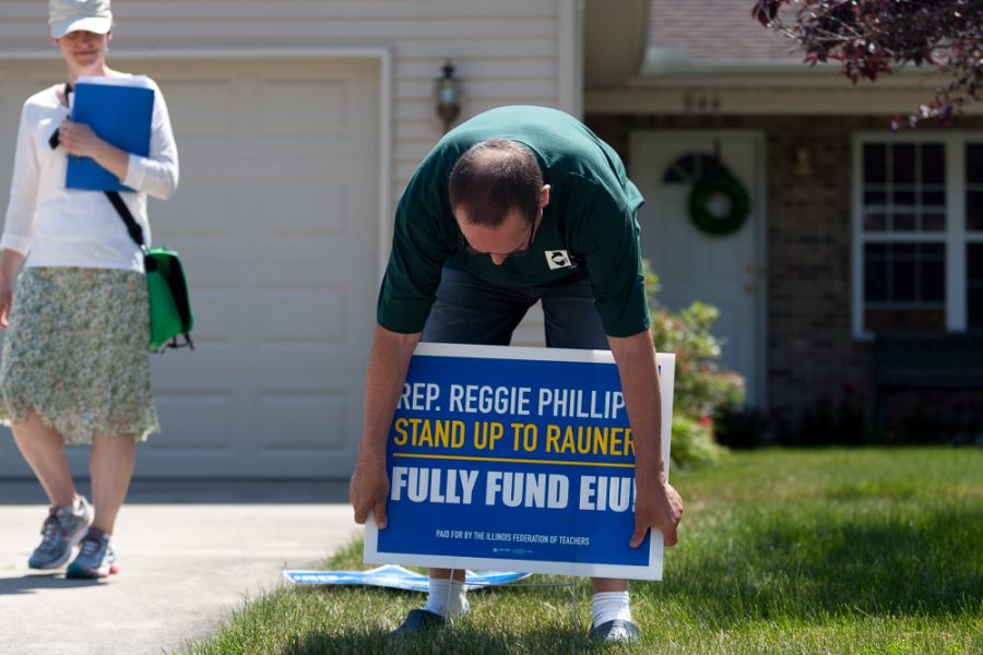 Stefan Eckert, a music professor, places a sign in a yard on Briarwood Court in Charleston on Saturday. Eckert was accompanied by Sace Elder, a womens studies professor and member of the EIU-UPI mobilization committee.