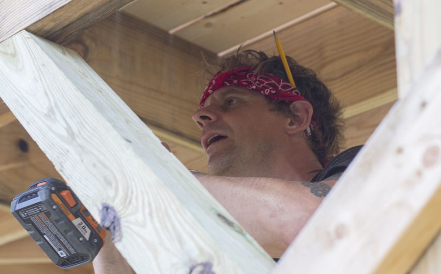 Tarble Art Center Assistant Director Mike Schuetz secures a support beam on a sculpture outside Tarble Art Center Wednesday. When the piece is complete, people will be able to sit at the picnic tables located on each of the four platforms.