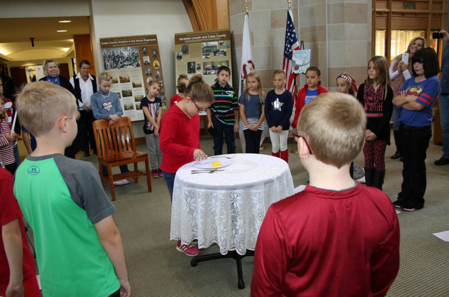 Students from Carl Sandburg Elementary School place meaningful items one by one during the White Table Ceremony, in the Booth Library for Veterans Day.