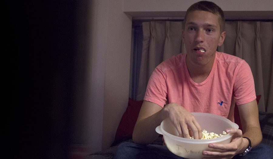 Alek McMath, a freshman marketing major, eats popcorn while watching Netflix in his friends dorm Tuesday night. Netflix released nine new titles for December, compared to over 30 released last November.