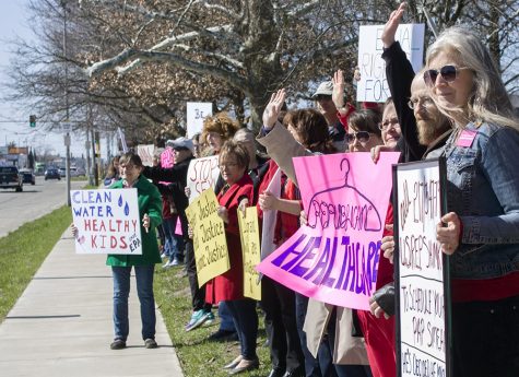 Local activists, who were protesting a host of issues for International Women’s Day, wave at a honking passerby Wednesday along Lincoln Avenue.
