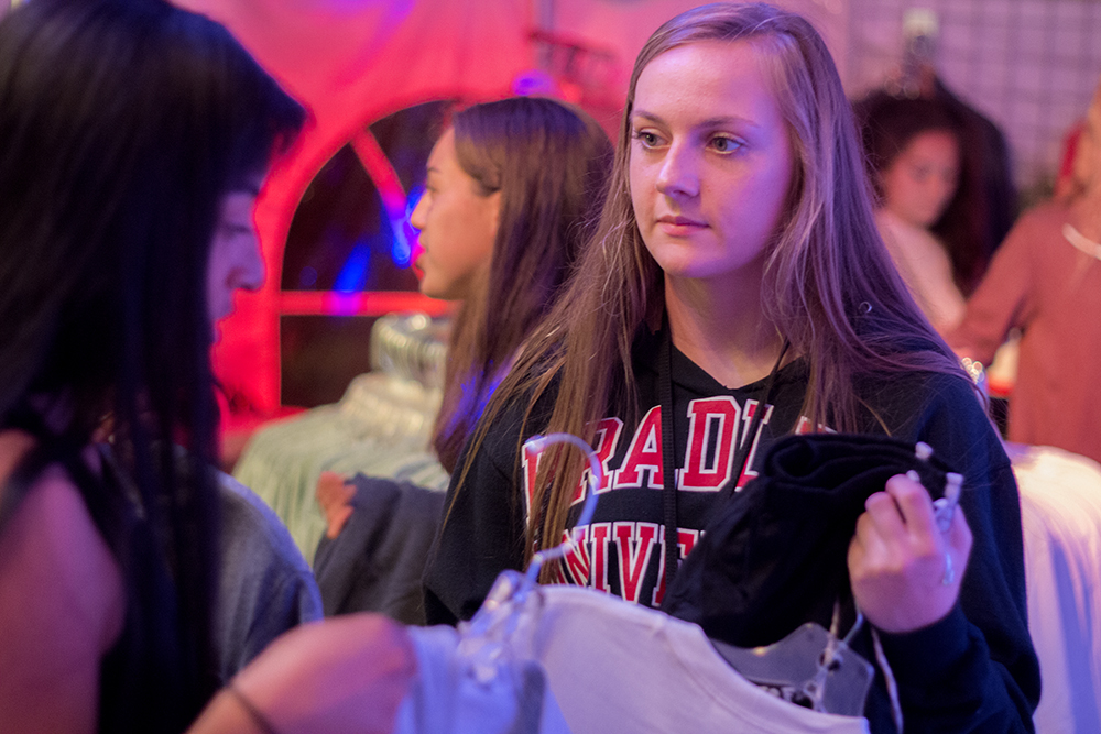 Kirsten Hager, a junior from Wethersfield High School, asks her friend, Wethersfield High School Senior Mariana Ponce, what she should get at annual track weekend t-shirt sale Wednesday night outside of Postively Fourth Street on the corner of Lincoln Ave. and 4th Street.