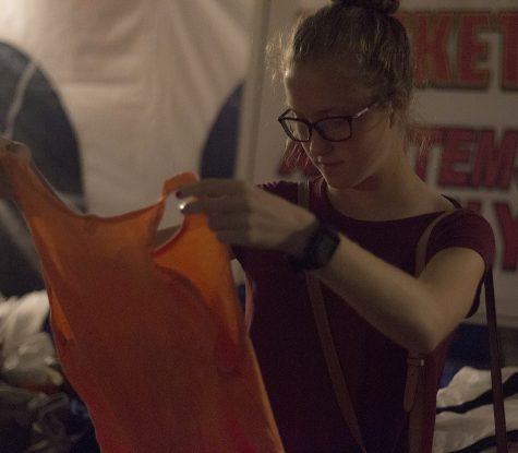 Kyla Epplin, a sophomore from Pinkneyville Community High School, inspects a shirt Wednesday night at First to Finish’s annual track weekend t-shirt sale in the Gateway Liquors’ parking lot. Epplin is competing this weekend and said she is a little nervous but it is not her first time competing.