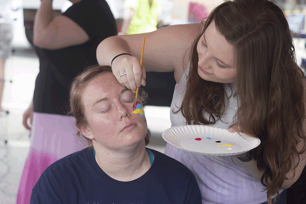 Katie Jenkins, a senior biology major paints Katie Saterfield’s face during Musefest at the Charleston High School art club booth.