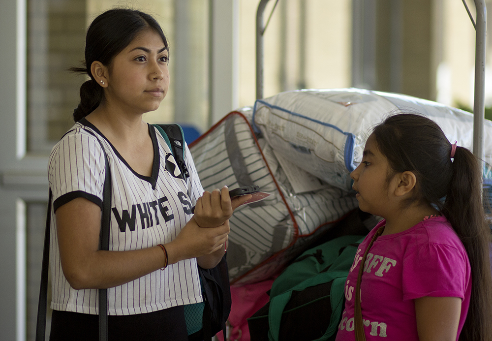 Yarely Robledo, a new freshman, watches several students unload their cars in front of Andrews Hall Thursday during move-in day while her younger sister Nataly asks her a question. Robledo said she is nervous about starting college but is ready for the new experience. Her father, Filibento Robledo, said she is the first daughter to go to college and even though it is sad to see her go, he said it was time.