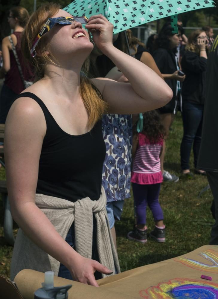 Lauren Mann, a graduate student studying art, takes a look at the eclipse as she attempts to draw it during the viewing party at the Campus Pond Monday. She said by the end of the event, they will have a time lapse of the moon’s shadow blocking the sun.