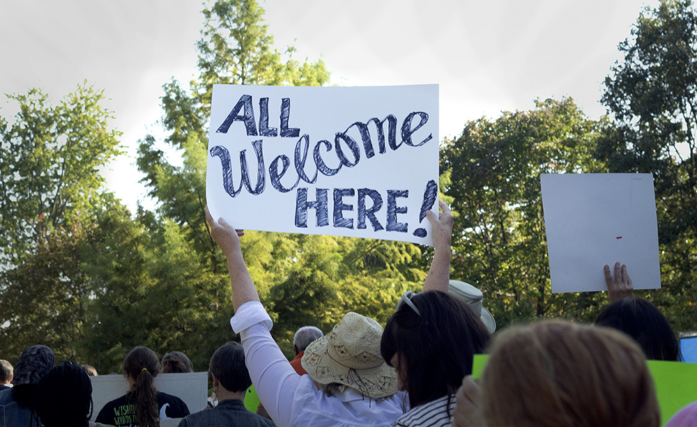 A supporter of the DACA rally that marched through Eastern Friday afternoon holds a sign that reads “All Welcome Here!”