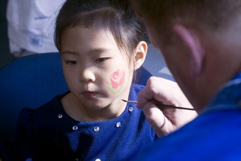 Christina Wang gets a flower painted on her cheek Saturday in the walkway lounge at the Martin Luther King Jr. University Union.