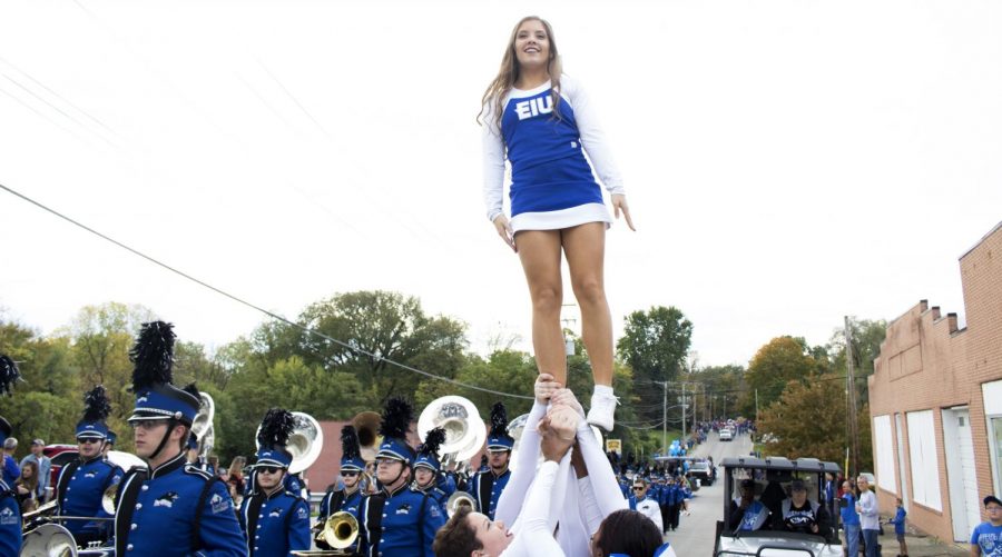 An+Eastern+cheerleader+is+held+up+along+side+the+marching+band+at+the+homecoming+parade+on+Seventh+street.