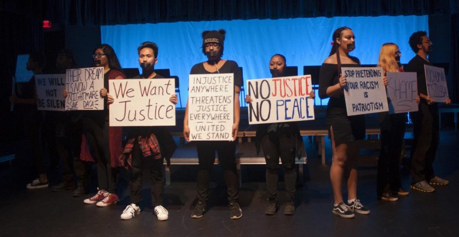 Travis Moody | The Daily Eastern News The company of “Serenade of the Silent Soul” holds up signs relating to issues concerning social justice. The black tape on their mouth symbolizes the silent soul of marginalized groups.