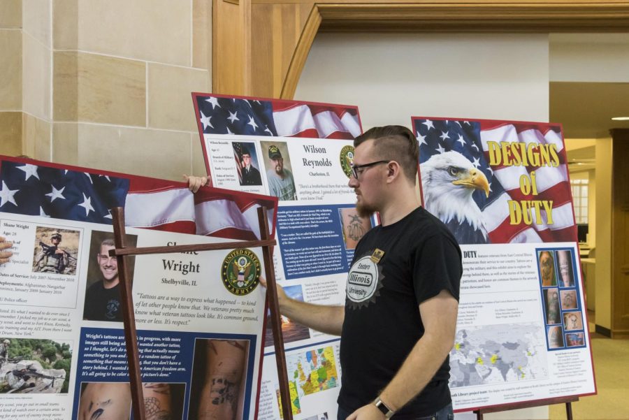 Rodney Rote Jr., a senior music performance major, sets up the exhibit Designs of Duty in Booth Library Monday afternoon. Designs of Duty is an exhibit featuring East Central Illinois veterans and their service-related tattoos, this will be on display at Booth Library from Jan. 22 through May 11.