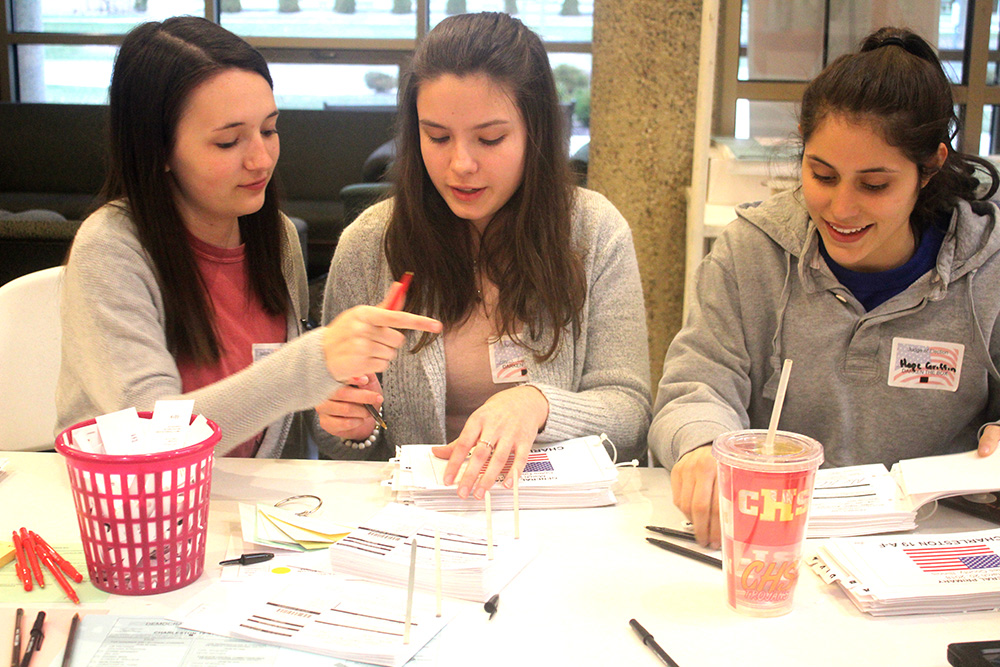 High School students Ashtyn Willheim, Ana Lawless and Hope Griffin organize election ballots at The Newman Catholic Center voting poll booth Tuesday evening. They were nominated to work as election judges by their teacher. 