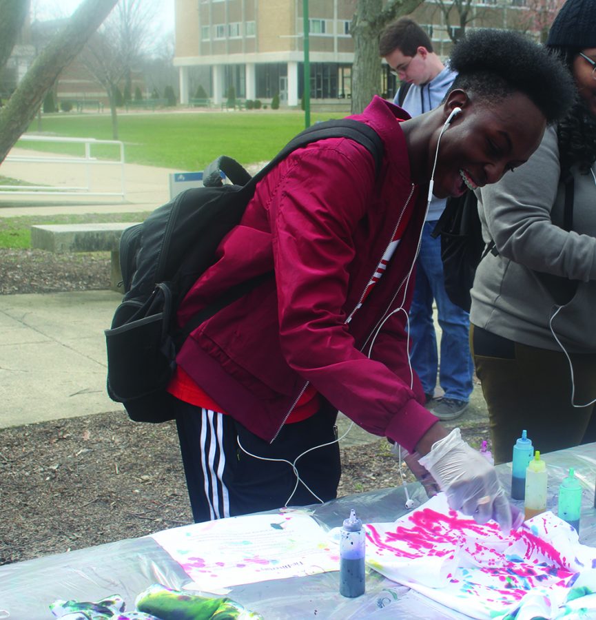 Dashawn McCray, a freshman sociology major, applies red dye to a T-shirt at Tie-Diversity in the South Quad on Monday afternoon.