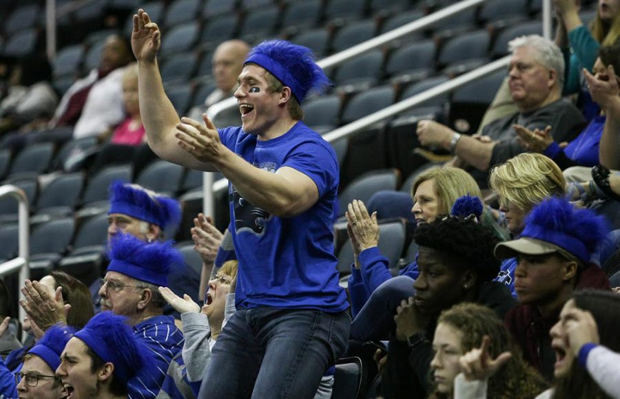 Eastern senior and basketball fan Devin Pierzhalski reacts to a play during the second half of Easterns opening round game of the OVC tournament. Pierzhalski purchased all of the blue headband wigs for fans traveling on the fan bus Wednesday.