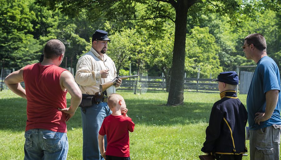 A cavalry member, explains how a Mauser Rifle works to the visitors at Lincoln Log Cabin State Historic Site.