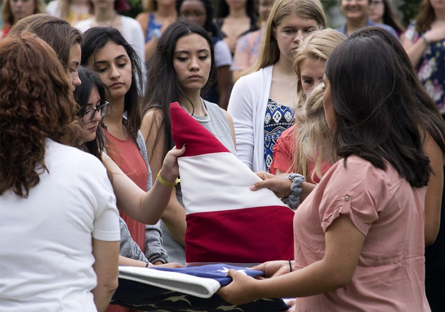 Members of American Legion Auxiliary Girls State, fold the flag after lowering it, during the flag disposal ceremony, Tuesday evening in the south quad.