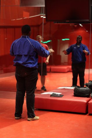 Samuel Augustin, a junior music performance major, practices conducting alongside Aaron Jones (who can be seen in the background) , a junior instrumental music education major in the Doudna Red Room Sunday night. Augustin says his favorite class is his camerata singers class, while Jones says his favorite is his choral methods class.