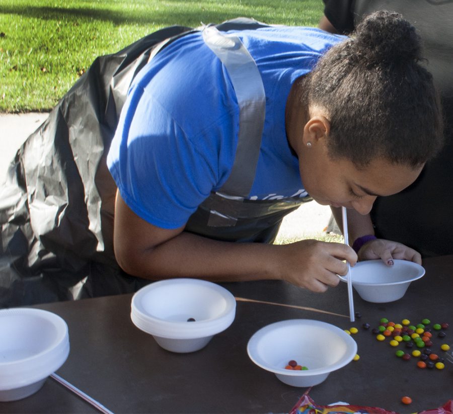 Shakria Williams, a freshman majoring in special education who was a part of Lawson Hall, uses a straw to get Skittles into a bowl at the ROCFest obstacle course Tuesday.