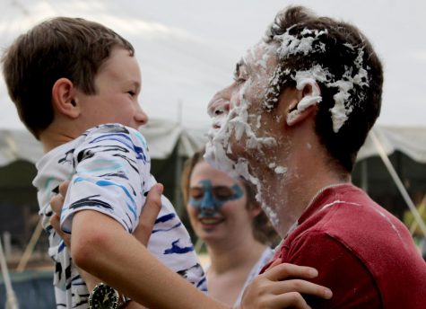 Jeremy Billy, a sophomore kinesiology and sports studies major, holds his younger brother, Connor Billy, and shows off his recently “pied” face from one of the booths at the RHA Family Carnival. Connor Billy said his favorite part of the carnival was seeing his older brother and the inflatables offered at the carnival. 