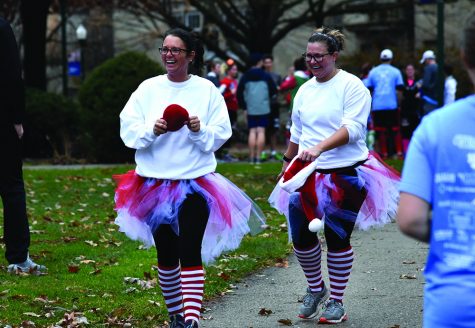 Two women dressed up in Christmas-themed outfits walked to the finish line  during the Holiday Hustle 5K run/walk.
