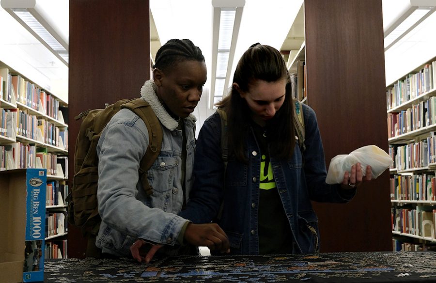 Chermaine King, a sophomore construction management major, and Sarah Gonpers, a sophomore pre-physical therapy major, add pieces to a puzzle Thursday night in Booth Library. It was a puzzle of a dock with boats and fishing nets.