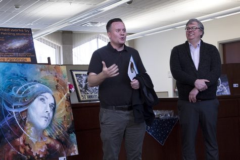 Chris Kahler, department chair and professor of art, painting and drawing, and David Bell, a reference librarian, both explain the progress and ideas behind the student art reception on Thursday at Booth Library.