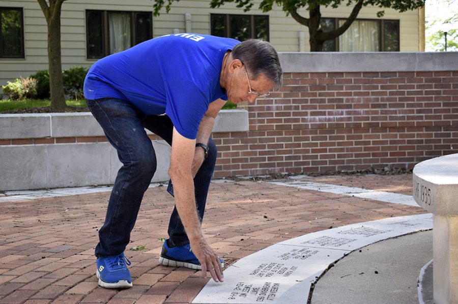 Larry Ankenbrand, a retired KSS professor, strokes the name slate belonging to his wife, Maureen, Sunday afternoon at the Commemorative Courtyard. 