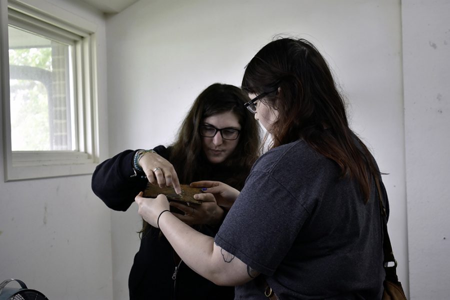 Leila Malekadeli (left) and Crystalyn Hutchens (right), both art students who graduated in May, discuss a new piece Hutchens worked on at the Burl Ives Studio Hall Monday morning. In the same area, 2018-2019 art graduate students were having brunch and working together to clean up the studios.