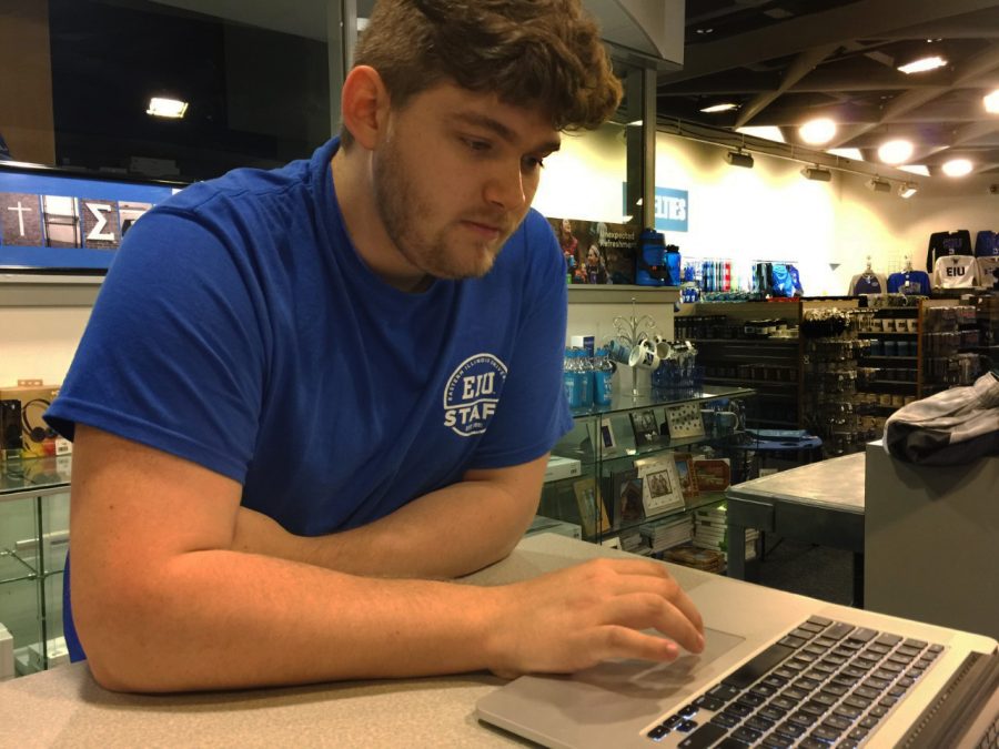 Evan Boggs, senior graphic design major and head of graphic design at Easterns Bookstore, scrolls through advertisements he has created for the store Wednesday afternoon.