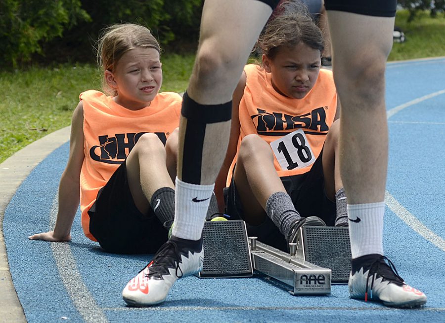 Two girls volunteering for the Illinois High School Association, put their feet on the starting block for a high school competitor during the 4x400-meter relay Class 1A preliminary Thursday at O’Brien Field.