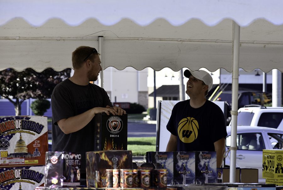 Tristan Warner (right) from Warner Enterprises talks with a customer at a set of merchant tables at an empty space next to Arby’s Monday. He said Warner Enterprises provides premier consumer fireworks across the state.