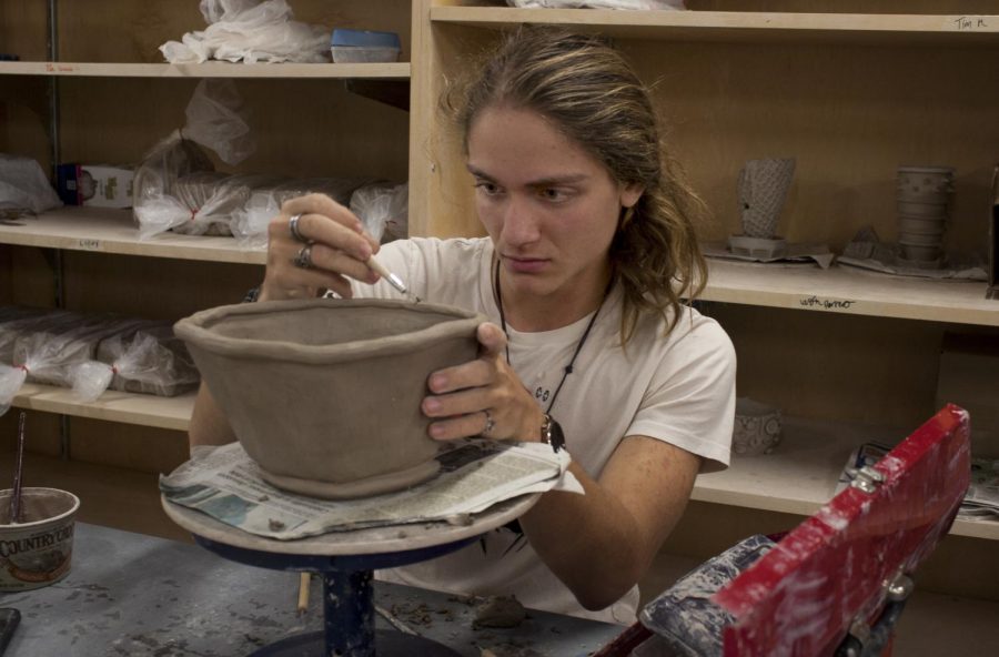 Westin Perrero, a sophomore art education major, works on his pottery project while his other projects dry on the shelves in the Doudna Fine Arts Center Sunday afternoon. Perrero said his favorite part about taking art classes at Eastern is the connection between the teachers and students.