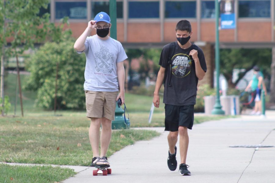 Conner Sanders (left), a sophomore music therapy major, long boards as Nick Myer (right), a sophomore chemistry major, walks with him after doing homework in the Dounda Hall red room Monday evening. Sanders and Myer said they were on their way to get food from Thomas Hall.