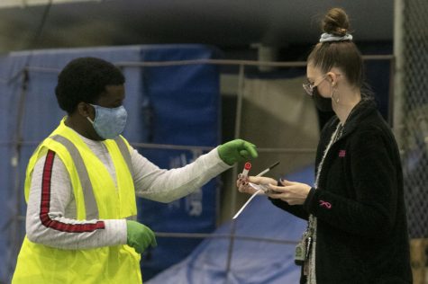 Kate Montgomery (right), a freshman psychology major, gets instruction from Corey Bentley, a senior health administration major, at the COVID-19 testing site in the Lantz Arena Fieldhouse on Dec. 2, 2020. [I] just want to make sure I don’t have COVID so I don’t spread it with any family or friends. I’m staying here but I visit home every weekend, Montgomery said. 