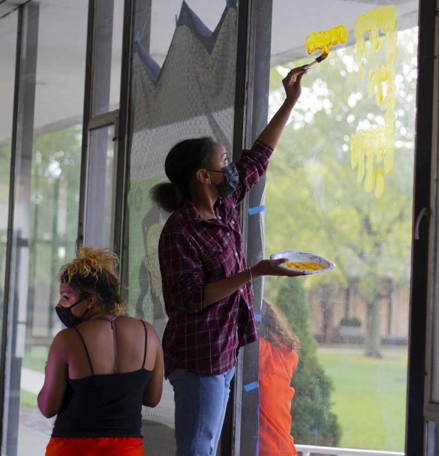 Sabrina Rodgers, a freshman computer science major, and Malaiah Mccrory, a freshman psychology major, paint a Kim Possible theme on the windows of Andrews Hall for Neighborhood Week Window Painting.