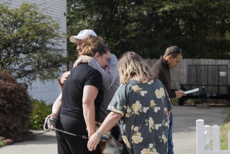 The parents of the woman whose house caught on fire, hug her while they wait outside.