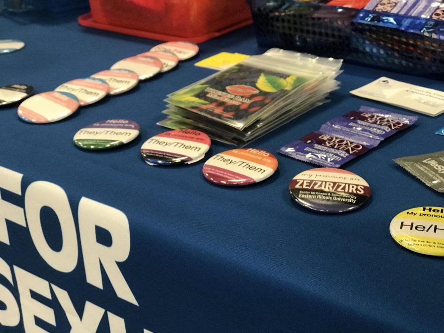 A lineup of pronoun pins on a table set in display for National Coming Out Day on Oct. 11.