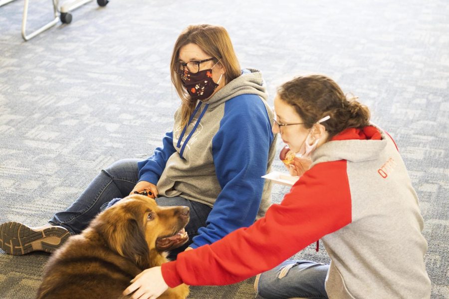 Heather Webb, the director of student accountability and support, brings her therapy dog named Bear to the Dogs and Doughnuts event in the Taylor Hall lobby. Brooke Ozier, a freshman biology major, enjoys a doughnut while she pets Bear. 