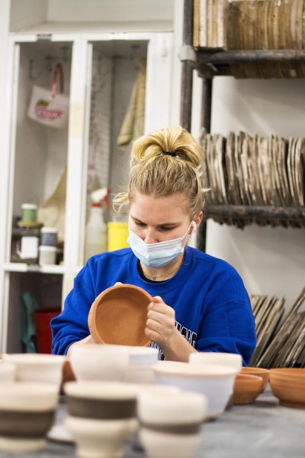 Abby Hartke, a junior 2D studio major, sands down ceramic pieces in Doudna Fine Arts Center Monday afternoon to get ready for glaze firing for her final project. 