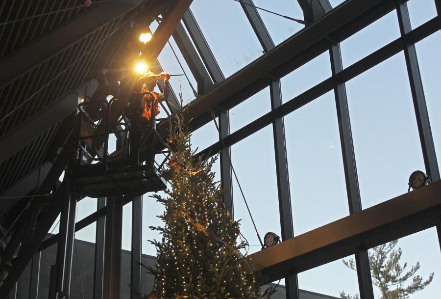 Connor Baltz, the director of operations for Doudna Fine Arts Center trims the top of the  Chirstmas tree in the Doudna lobby area to put the topper on Tuesday afternoon. 