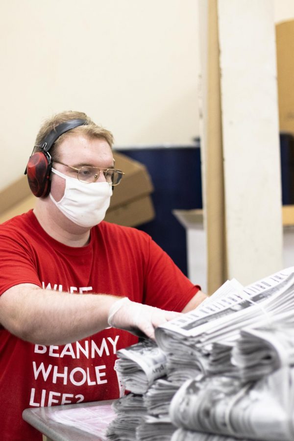 McClain Homann, a senior english major, puts the finished and tied newspapers stacked on top of each other ready to be dispersed throughout campus buildings as the last step in the printing press process. 
